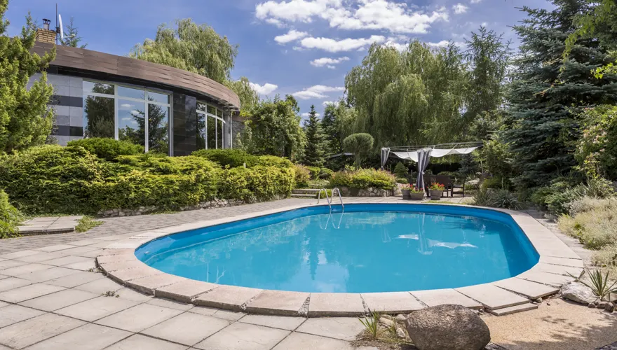 Oval backyard pool beside a stone patio